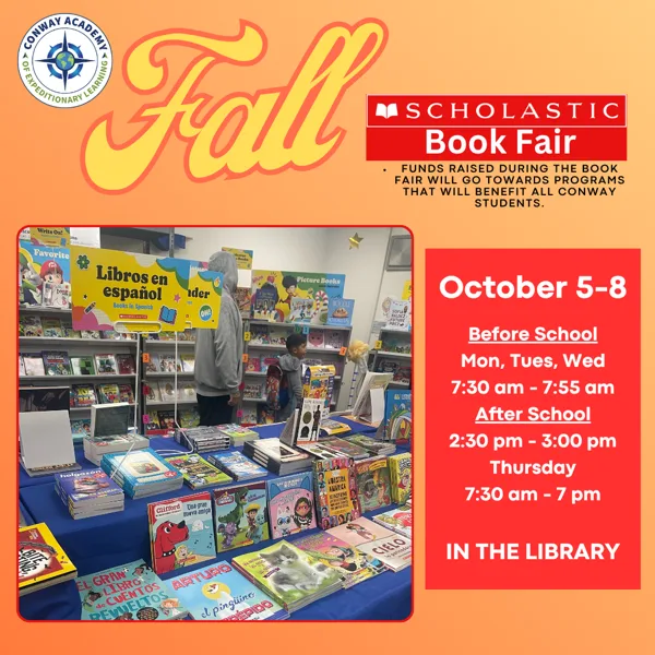 A photo of a Scholastic Book Fair display in a school library, with colorful books spread across a blue-clothed table and shelves of books in the background, including a sign for books in Spanish.