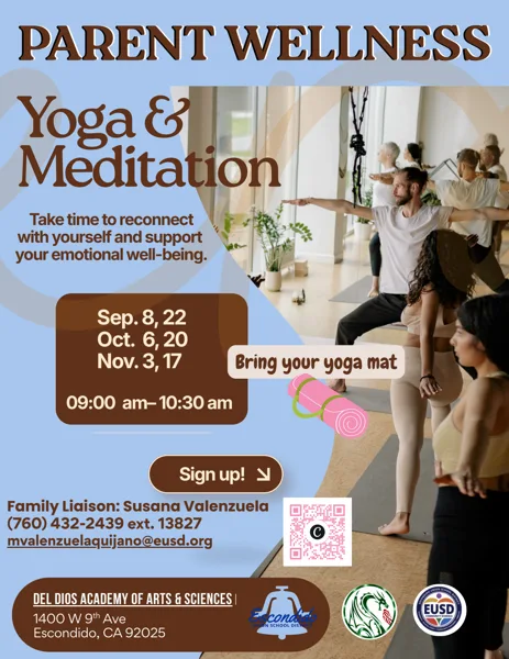 A group of adults practice a standing yoga pose together in a bright, open studio with large windows and yoga mats on the floor.