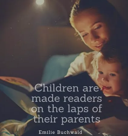An adult and a young child read a book together in a dimly lit setting.