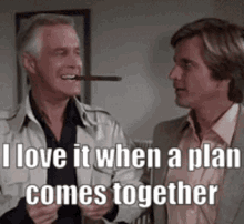 Two men stand together indoors, one older and one younger, with text overlay reading I love it when a plan comes together.