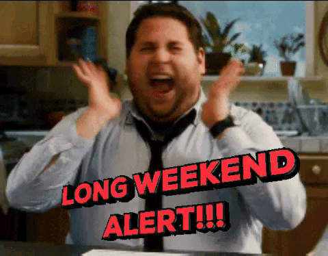 A man in a white shirt and tie raises his hands excitedly in a kitchen, with the text LONG WEEKEND ALERT!!! overlaid in red letters.