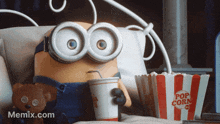 A animated Minion character sits in a chair holding a drink and a bucket of popcorn.